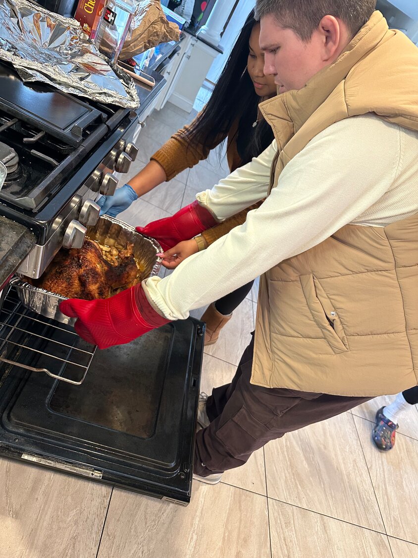 Kyle Telford, who lives at the Life’s WORC group home in Islip Terrace, lends a helping hand with the Thanksgiving turkey that the residents will share with staffers.